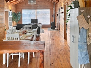Un intérieur en bois comprenant un coin repas, un canapé et une cuisine équipée d’un réfrigérateur et d’un four.