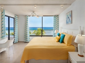 A hotel room with a large bed, a desk, and a view of the ocean. - Sunset Beach Unit 10 St Lawrence Gap Condos (Oistins)
