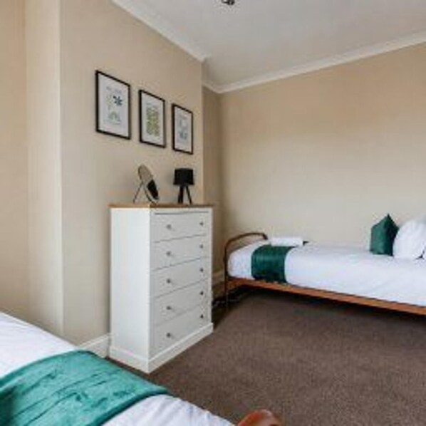 A bedroom with a bed, a dresser, and wall-mounted pictures.