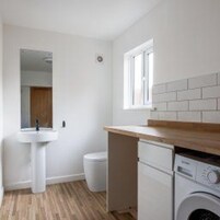 Un baño pequeño con lavamanos, espejo, inodoro y lavadora.