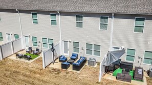 A residential building with multiple windows, a fenced patio area with outdoor furniture, and a covered outdoor seating area. - Discovery Landing • Huntsville 3BR Townhome, Patio (Huntsville)