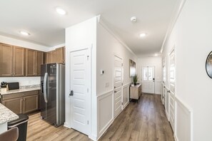 A modern kitchen with wooden cabinets, a stainless steel refrigerator, and a marble countertop. - Discovery Landing • Huntsville 3BR Townhome, Patio (Huntsville)
