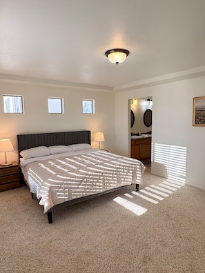 A bedroom with a bed, two bedside lamps, a ceiling light, a window, and a door leading to a bathroom. - Spacious 5-Bedroom House Near Park & Golf Course (Denver)