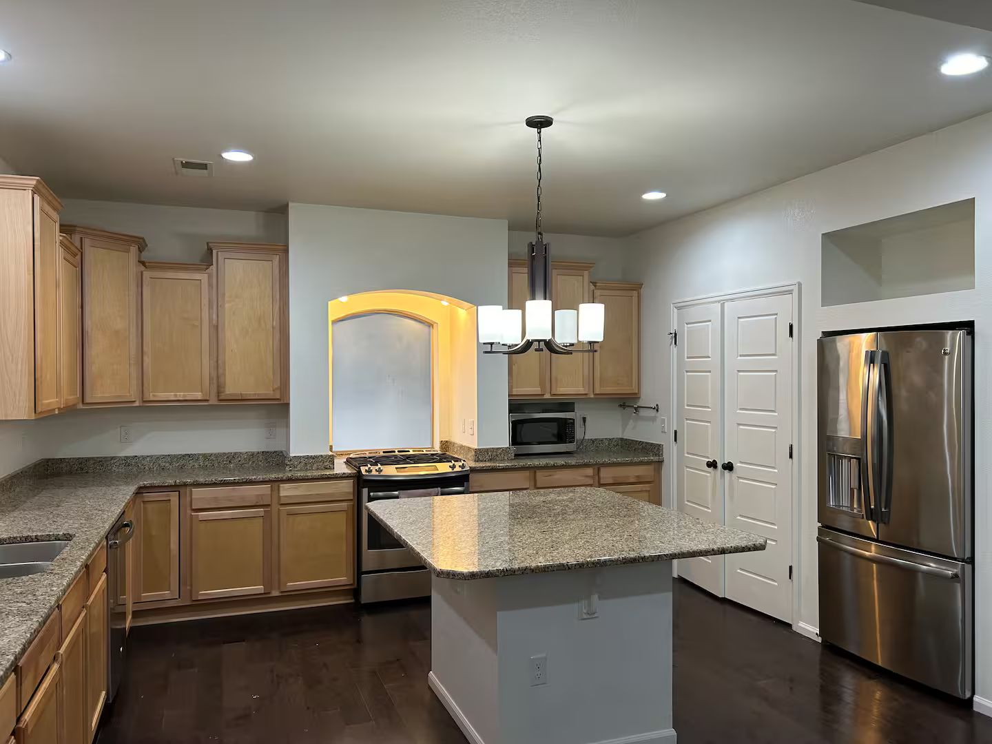 A modern kitchen with granite countertops, stainless steel appliances, and wooden cabinetry.