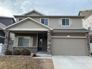 A two-story house with a stone facade, a front porch, and a garage. - Spacious 5-Bedroom House Near Park & Golf Course (Denver)