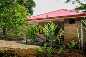 Una casa de madera con techo rojo, rodeada de vegetación y un camino de grava.