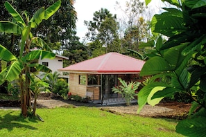 A house with a red roof, surrounded by lush greenery and a well-maintained lawn. - NEW! Cozy 1-bedroom bungalow in peaceful Chachagua with AC (San Ramon)