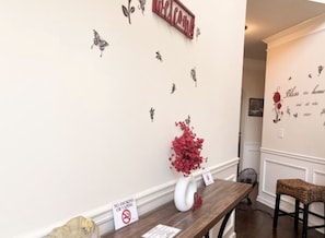 A reception area with a 'Welcome' sign, a no-smoking sign, a vase with red flowers, and a wall with butterfly decals.