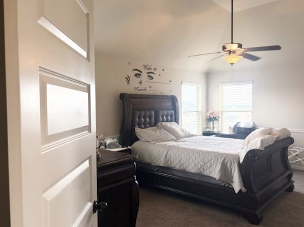 A bedroom with a bed, dresser, and a ceiling fan.