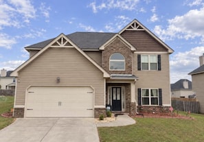 A two-story house with a garage, a front porch, and a landscaped yard.