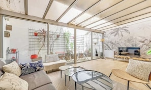 A modern living room with a sofa, coffee table, and TV. - CHARMING 2-BEDROOM DUPLEX WITH PRIVATE PATIO IN CENTRAL PARIS (Paris)