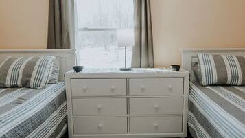 Un dormitorio con dos camas, una mesita de noche y una ventana con cortinas.