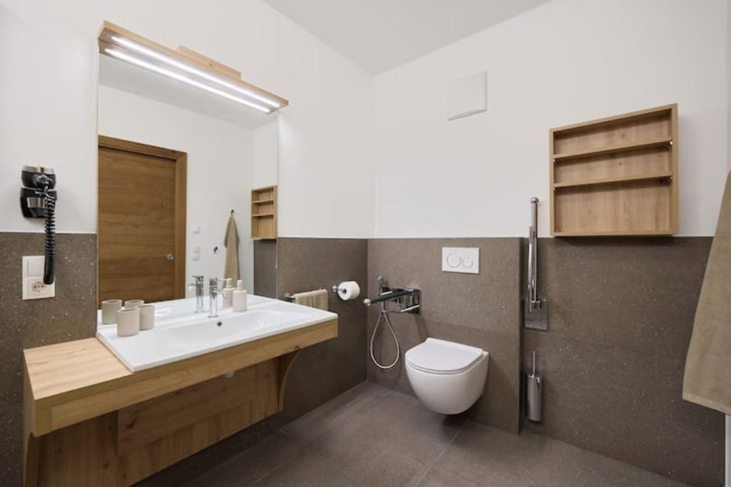 Une salle de bain moderne avec un meuble-lavabo en bois, un grand miroir, des toilettes et une douche.