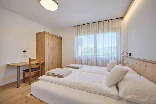 Ein Schlafzimmer mit zwei Betten, einem Schreibtisch, einem Stuhl und einem Kleiderschrank.