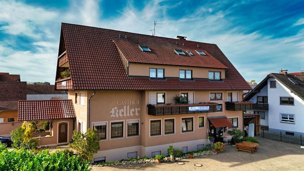 A multi-story building with a brown facade, a balcony, and a sign that reads 'GASTHOF Keller.'