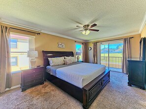 A bedroom with a bed, a nightstand, a dresser, a ceiling fan, and a view of the outdoors. - Cozy Stay near Disney w/Pool, Lazy River & Resort (Davenport)