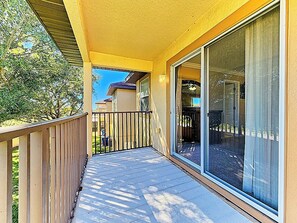 A balcony with a wooden railing, a glass door, and a view of a house in the background. - Cozy Stay near Disney w/Pool, Lazy River & Resort (Davenport)