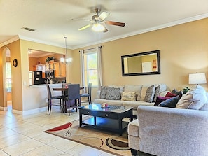 A living room with a sofa, coffee table, and a dining area with chairs and a table. - Cozy Stay near Disney w/Pool, Lazy River & Resort (Davenport)