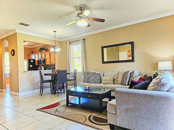 A living room with a sofa, coffee table, and a dining area with chairs and a table. - Cozy Stay near Disney w/Pool, Lazy River & Resort (Davenport)