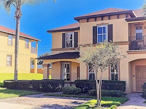 A two-story residential building with a balcony, a front door, and a small tree in the front yard. - Cozy Stay near Disney w/Pool, Lazy River & Resort (Davenport)