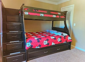 A bunk bed with a red and blue Mickey Mouse themed bedspread, a wooden dresser with drawers, and a door in the background. - Cozy Stay near Disney w/Pool, Lazy River & Resort (Davenport)