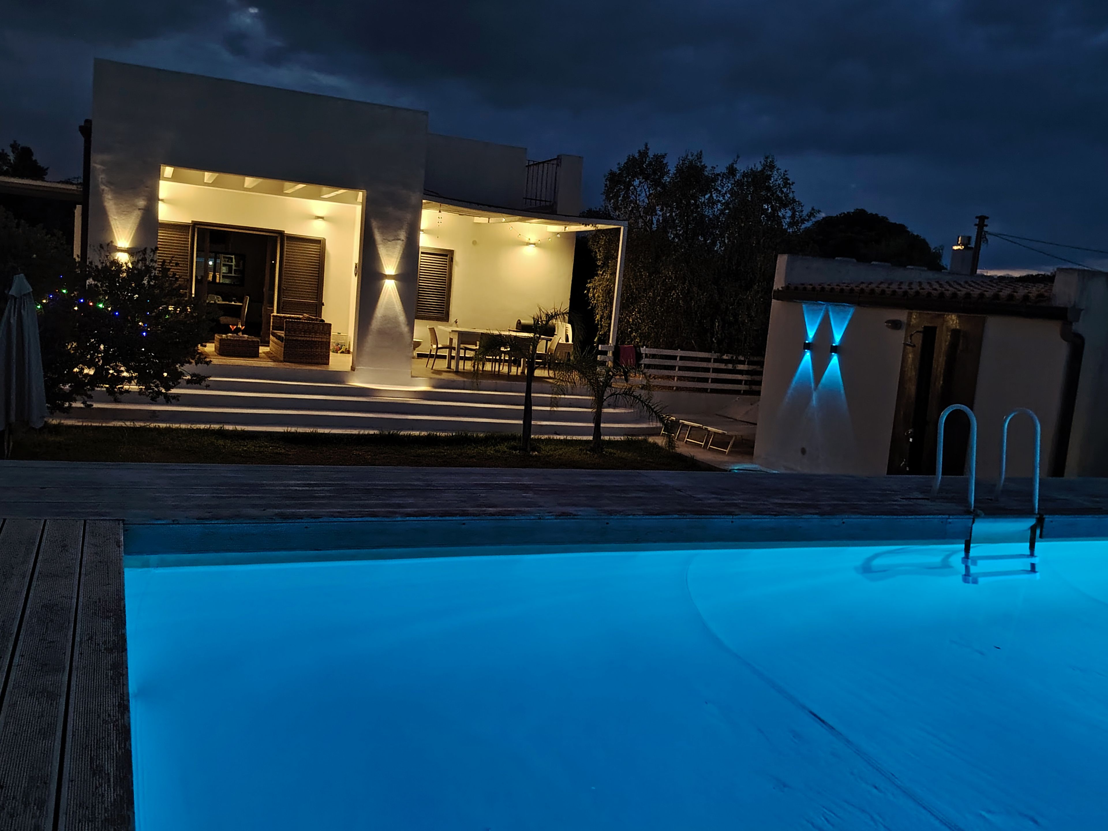 Une maison moderne dotée d’une piscine extérieure, d’un patio et d’une entrée bien éclairée.