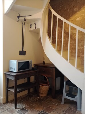 A kitchen area with a microwave on a wooden table, a wicker basket, and a staircase with a white railing. - Charm and tranquility near Futuroscope and Chauvigny (Bonnes)