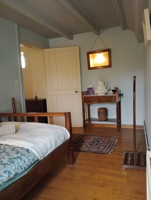 A room with a wooden bed, a table with a pitcher and a small figurine, a mirror, and a wooden floor. - Charm and tranquility near Futuroscope and Chauvigny (Bonnes)