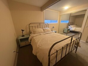 A bedroom with a single bed, bedside table, lamp, and a mirror. - Lovely 2 bdrm Semi-detached (Calgary)