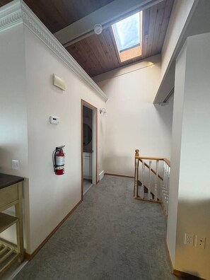 A narrow hallway with a wooden ceiling and a skylight, leading to a door. - Lovely 2 bdrm Semi-detached (Calgary)