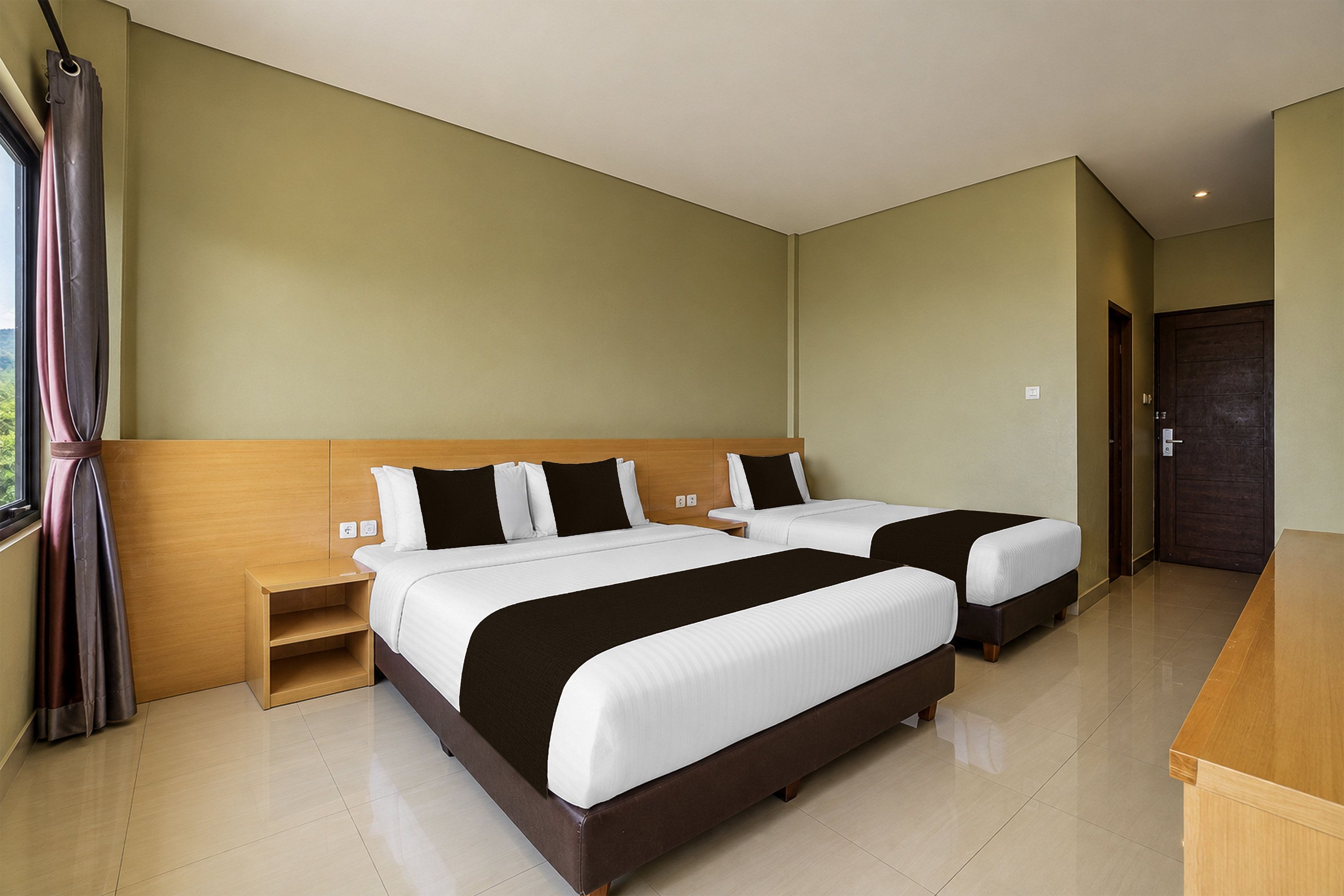 Habitación de hotel con dos camas, un cabecero de madera, una mesita de noche y una puerta.