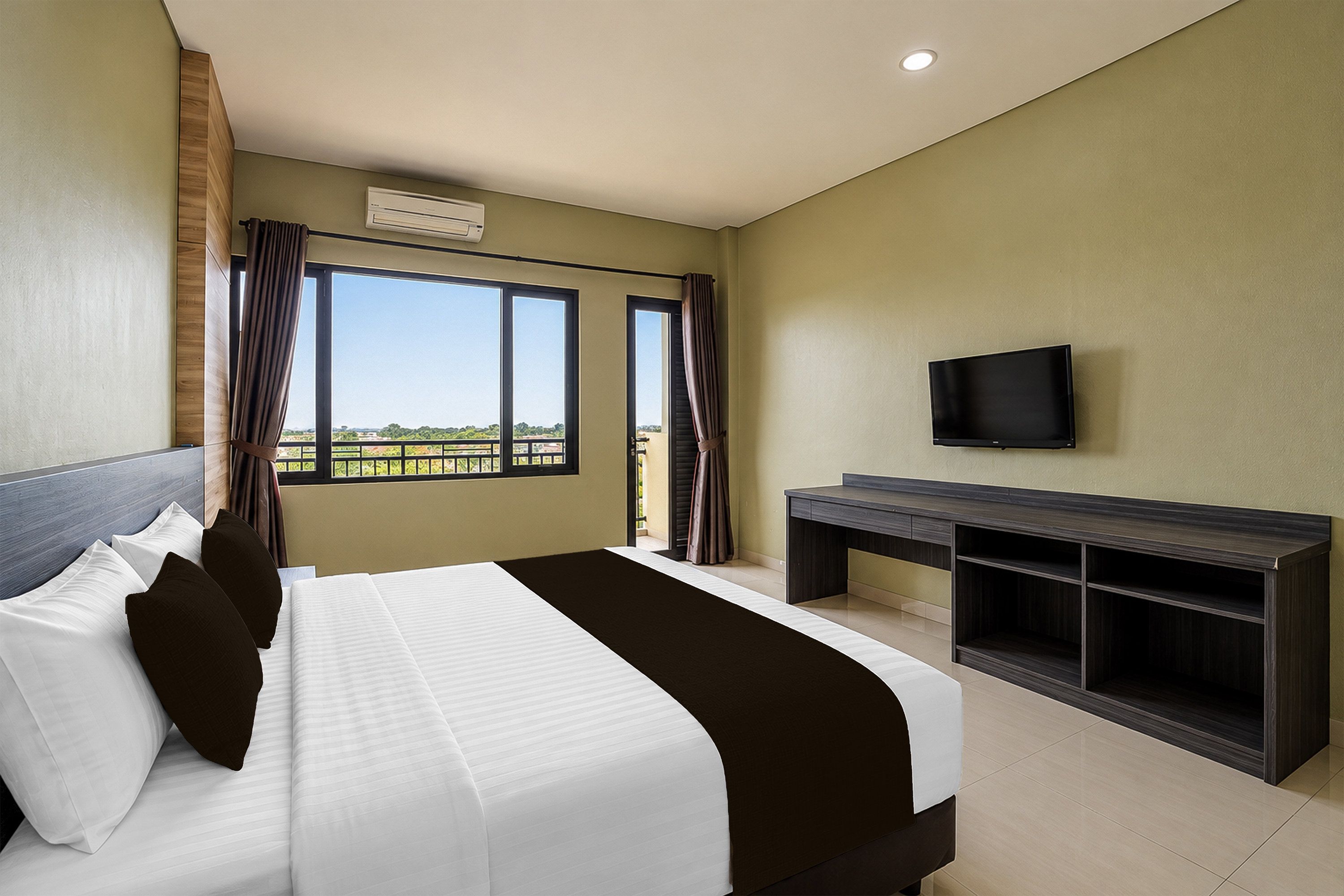 Una habitación de hotel con cama, escritorio, televisor y ventana con cortinas.