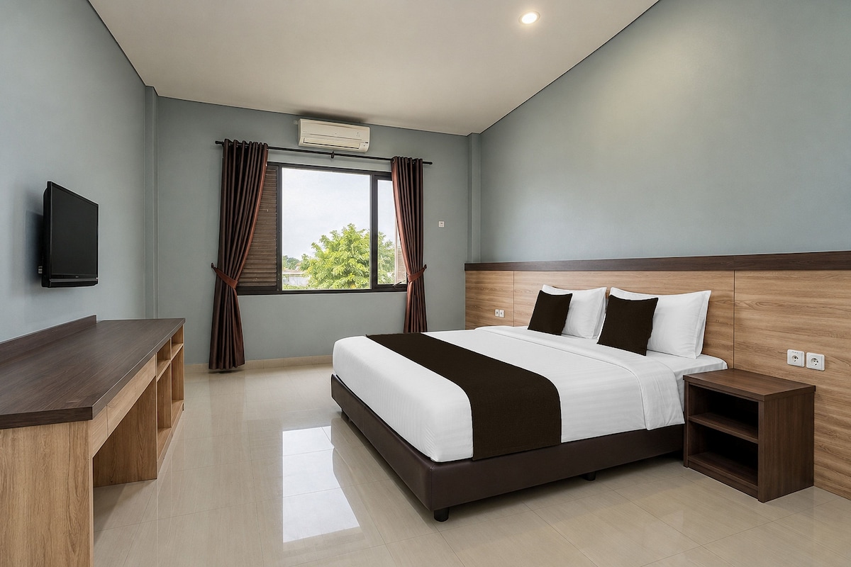 Una habitación de hotel moderna con una cama grande, un escritorio, un televisor y un ventanal con cortinas.