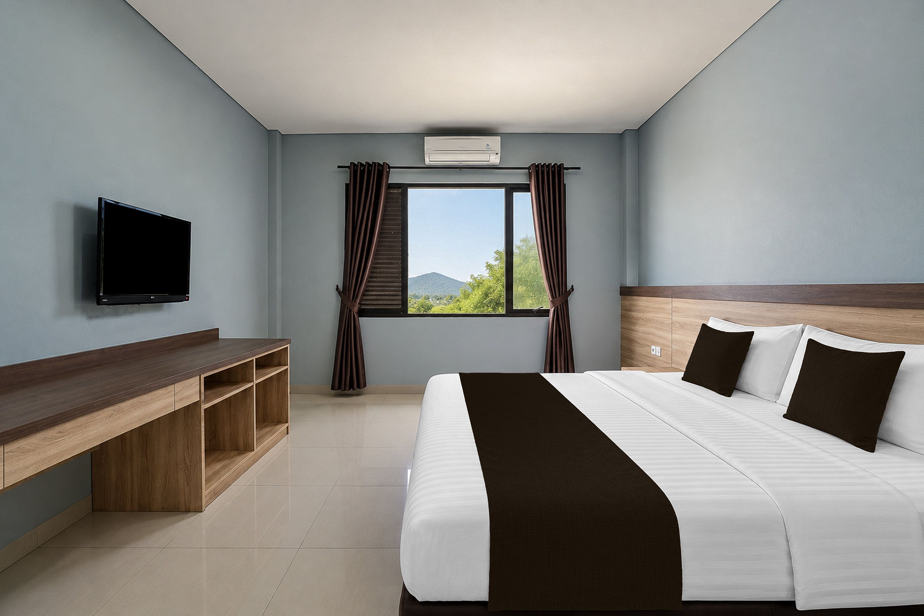 Una camera d'albergo con un letto, una TV, una finestra con tende e una scrivania.