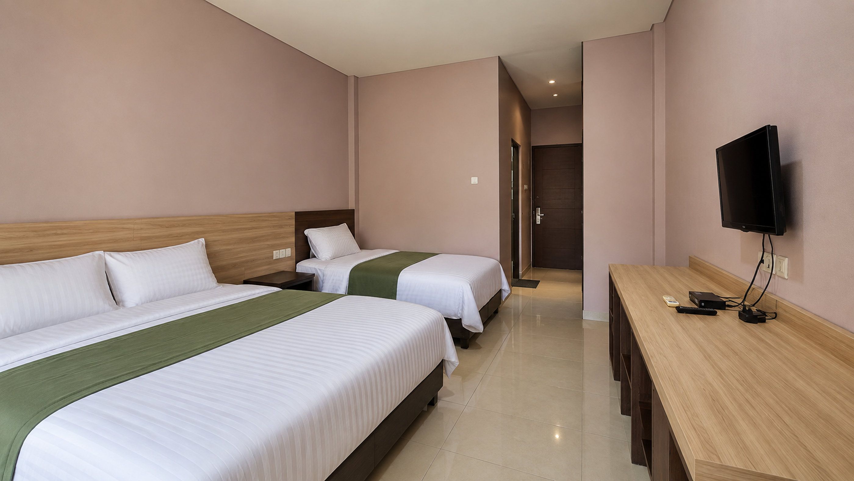 Habitación de hotel con dos camas, un televisor y un escritorio.