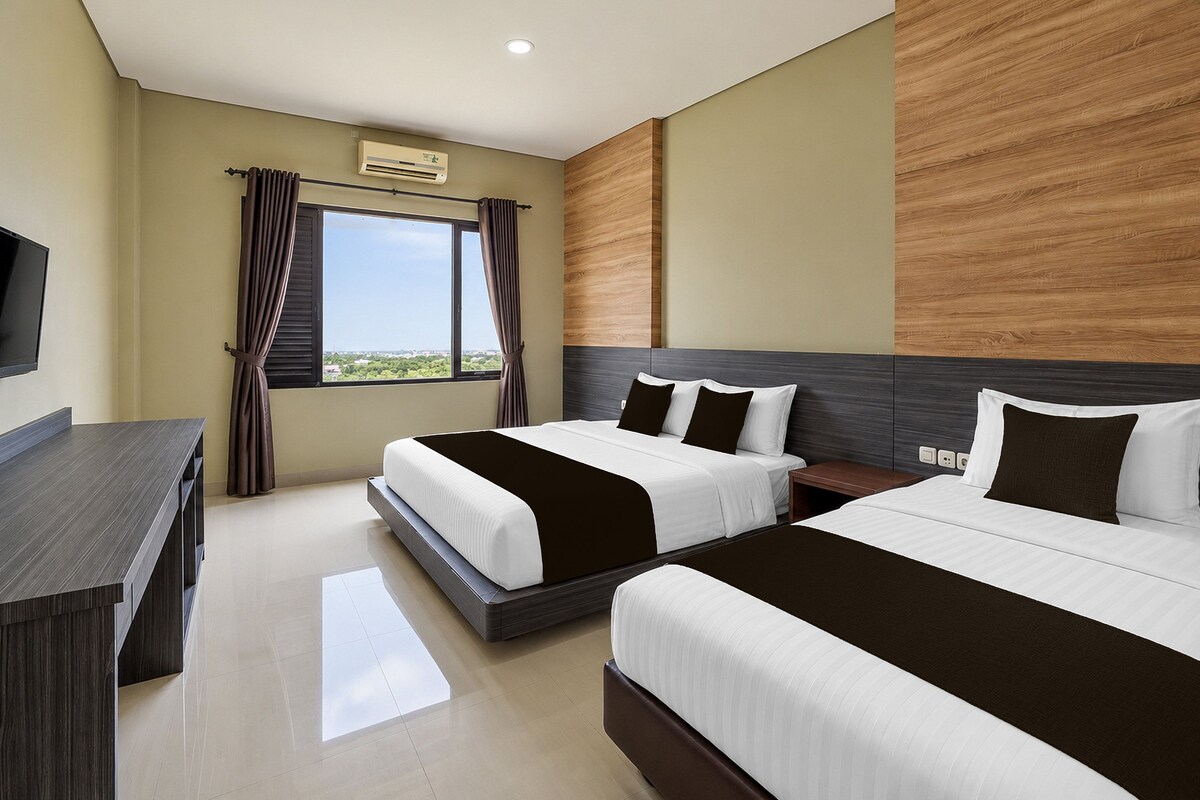 Una habitación de hotel con dos camas, un escritorio y una ventana con cortinas.