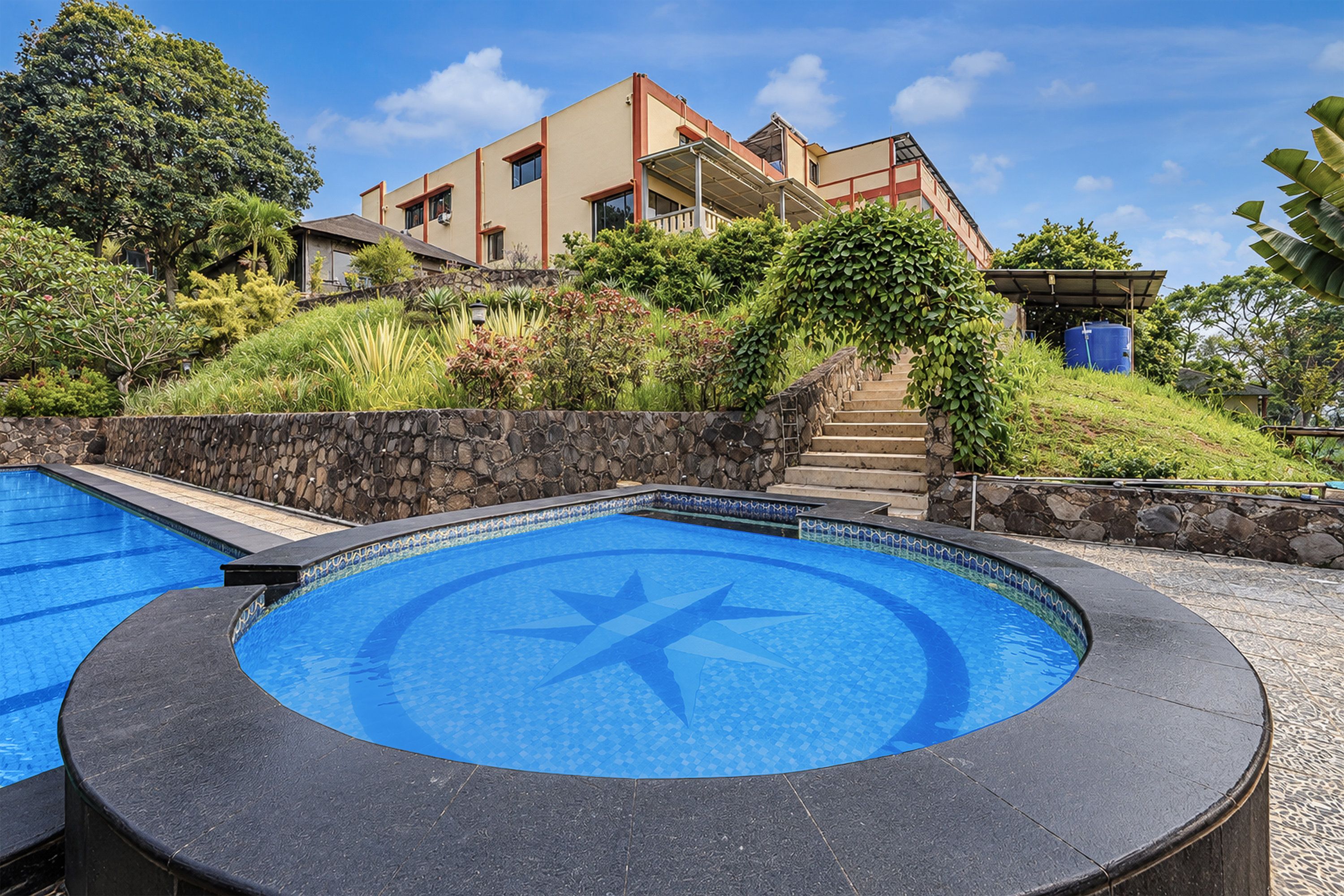 Un edificio moderno con zona de piscina, incluyendo una piscina circular con diseño de estrella y una piscina rectangular.