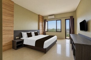 Habitación de hotel con cama, mesitas de noche, televisor y balcón con vistas.