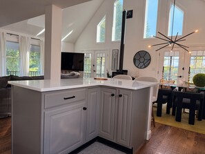 Une cuisine moderne avec des meubles blancs, un grand îlot central et un coin repas comprenant une table ronde et des chaises.