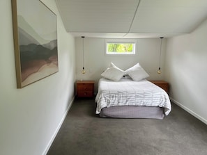 Quarto com uma cama, duas mesas de cabeceira, uma janela e um quadro na parede.