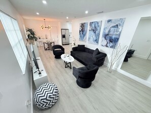 Ein modernes Wohnzimmer mit einem schwarzen Sofa, einem runden Couchtisch und einem großen Spiegel, der den Raum widerspiegelt.