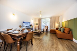 A modern living room with a dining area, a sofa, and a television. - Little Venice 2BR Retreat | Paddington & Hyde Park (London)