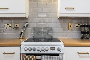 A kitchen with a white stove, a metal rack, and a coffee maker. - Little Venice 2BR Retreat | Paddington & Hyde Park (London)