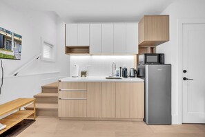 A compact kitchen with a built-in microwave, a stainless steel refrigerator, and wooden cabinetry. - Brand New Cozy and Private Guest Suite in Mount Pleasant (Vancouver)