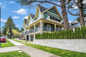 A two-story residential building with a balcony, a driveway, and a well-maintained lawn. - Brand New Cozy and Private Guest Suite in Mount Pleasant (Vancouver)