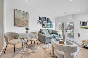 A modern living room with a glass table, a grey sofa, and framed pictures on the wall. - Brand New Cozy and Private Guest Suite in Mount Pleasant (Vancouver)