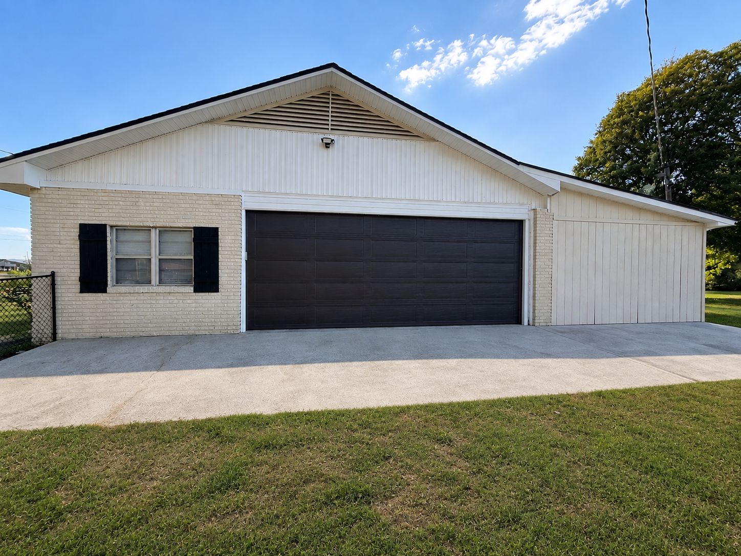 A single-story building with a garage door, a small window with shutters, and a sloped roof.