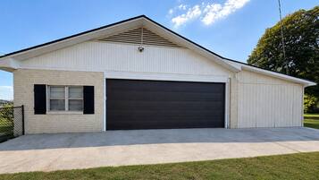 A single-story building with a garage door, a small window with shutters, and a sloped roof.