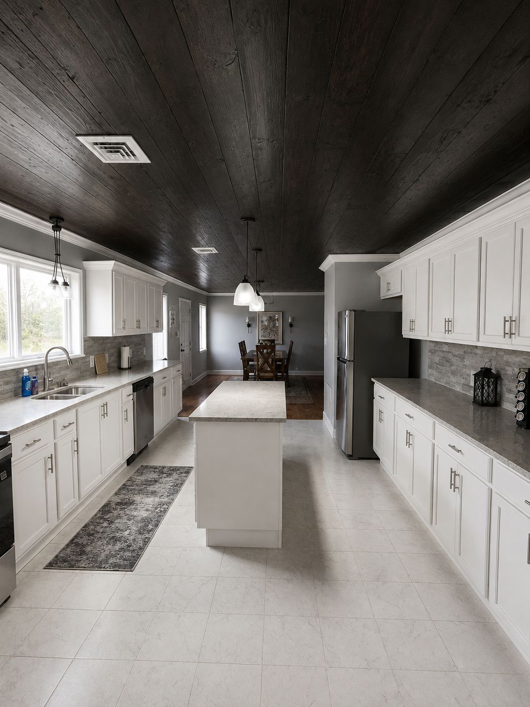 A modern kitchen with white cabinetry, a central island, and a dark wooden ceiling.