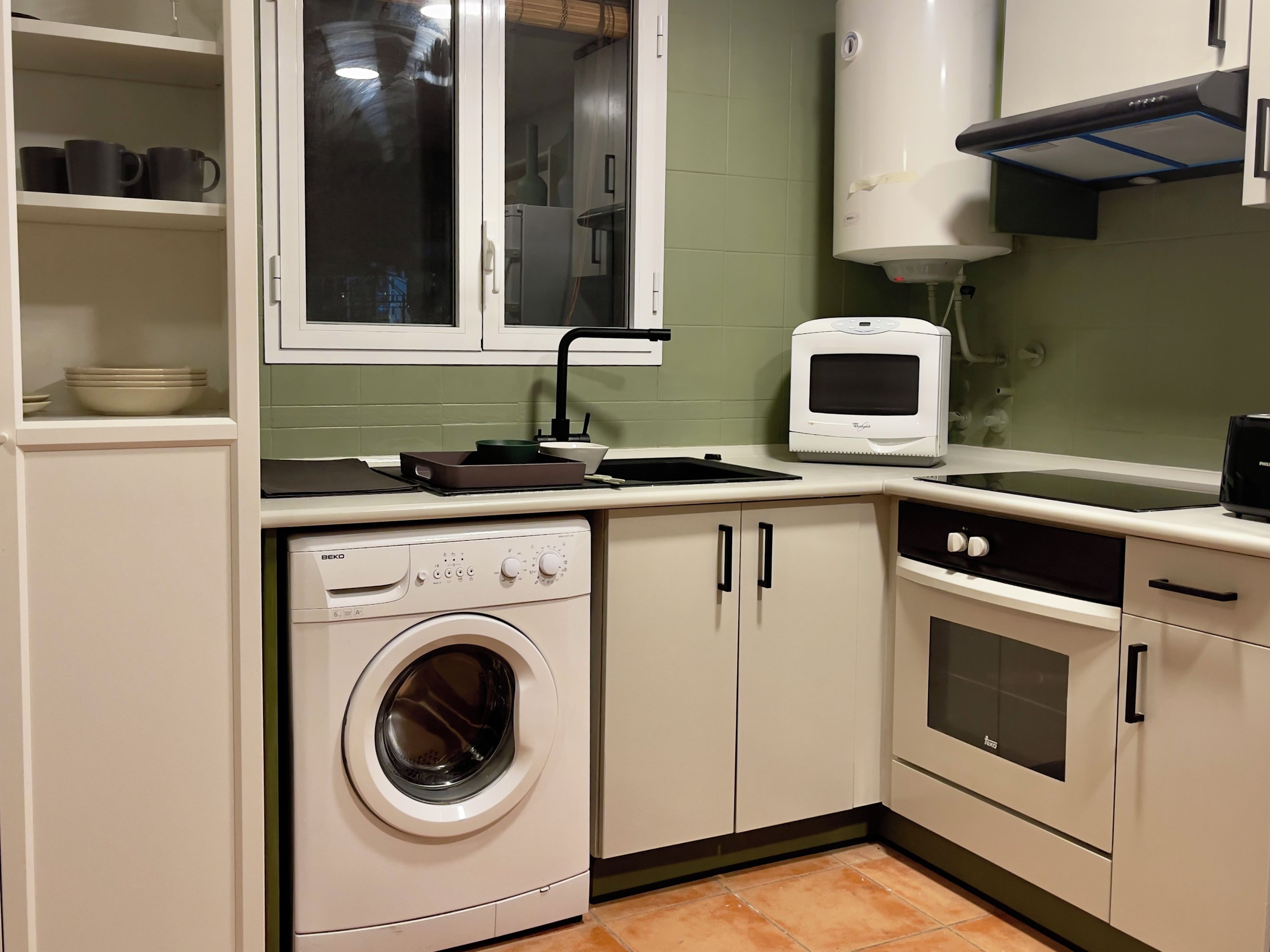 A compact kitchen with a built-in washer, oven, and microwave.